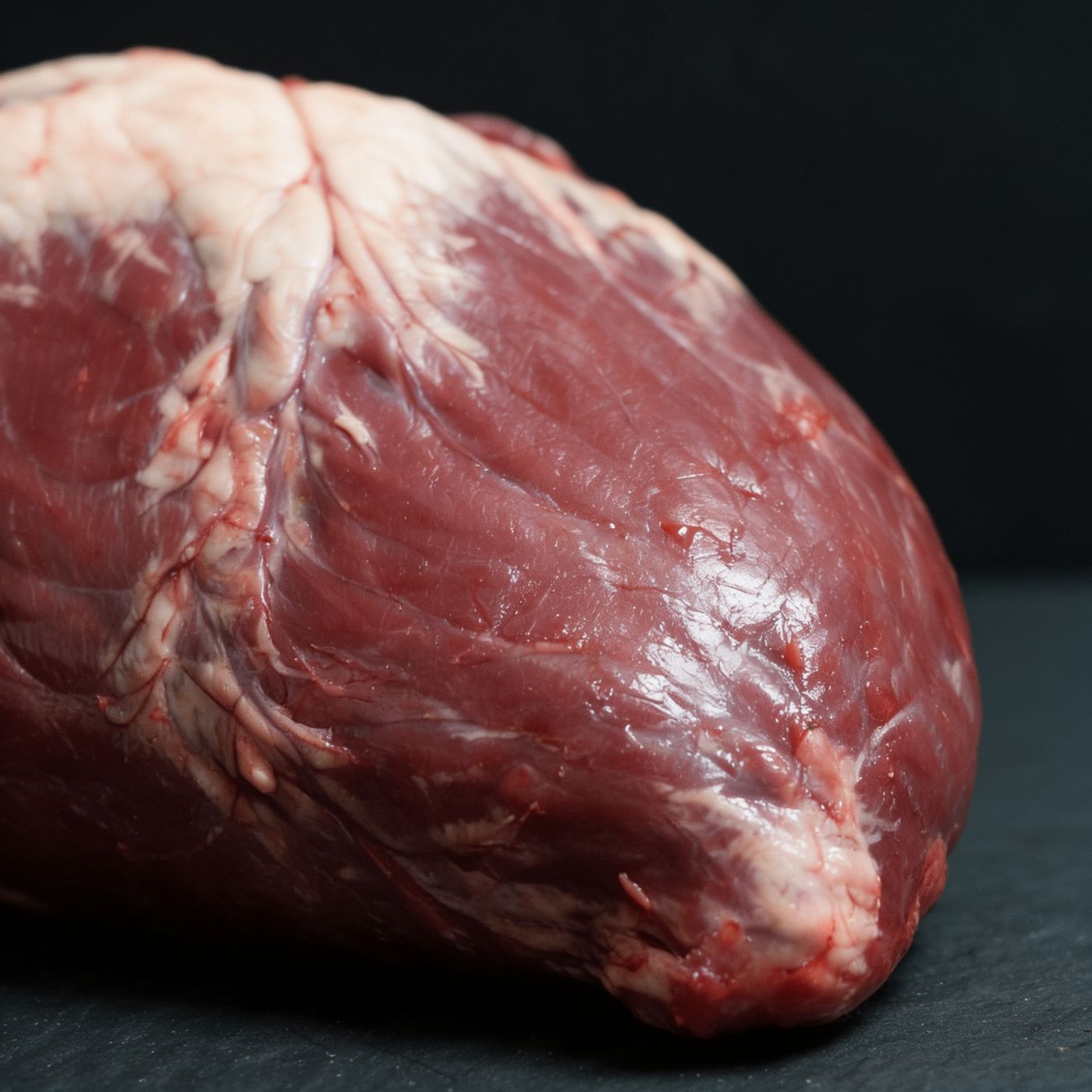 Close-up of raw whole beef heart on butcher paper